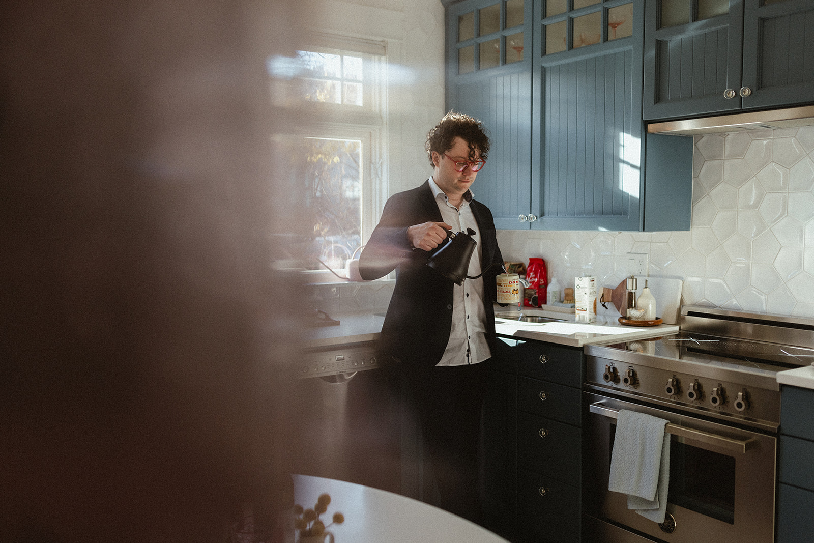 young man pouring coffee into a mug in his kitchen
