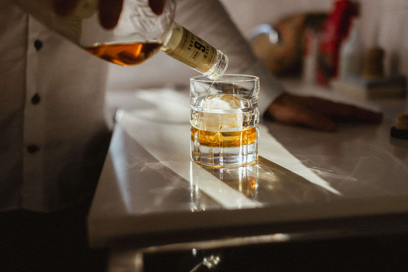 whiskey bottle pouring into a glass on a counter