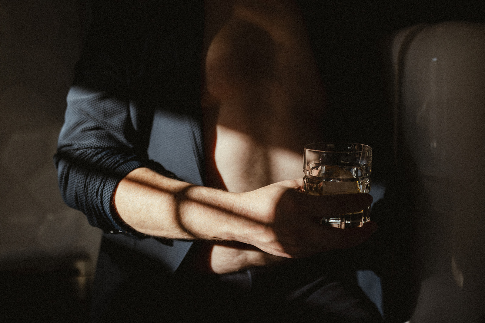 young man holding a whiskey glass with his shirt unbuttoned